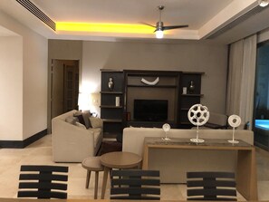 A modern living room with a sofa, a coffee table, a TV, and decorative items. - PGA Open and Luxury Living in a 3 Bedroom Suite in sunny Mexico! (Nuevo Nayarit)