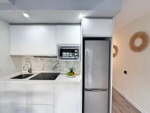 A modern kitchen with white cabinets, a stainless steel refrigerator, a built-in oven, and a marble backsplash. - Tropical Views - Playa del Inglés (Playa del Inglés)