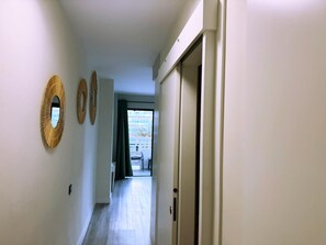 A hallway with a door on the right, a window at the end, and three wall-mounted mirrors. - Tropical Views - Playa del Inglés (Playa del Inglés)