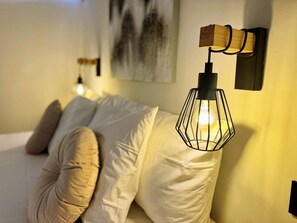 A bed with white bedding and a single beige pillow, a wall-mounted light fixture with a wooden accent, and a painting on the wall. - Tropical Views - Playa del Inglés (Playa del Inglés)