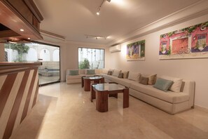 Amplia sala de estar con un sofá, dos mesas auxiliares y vistas a un patio exterior.
