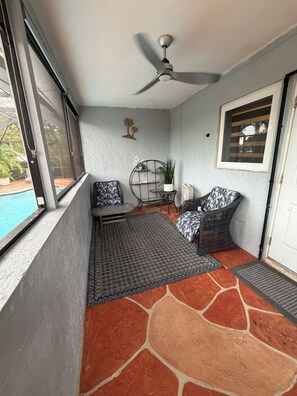A balcony with a ceiling fan, a pool view, a seating area with a patterned rug, and a door with a window. - Roxana's Modern House (Coral Springs)