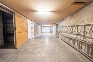 Ein Korridor mit Betonboden, einer Holztür links und Metallgeländern rechts.