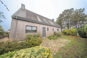 Ein Holzhaus mit geneigtem Dach, einer Haustür und einem Fenster.