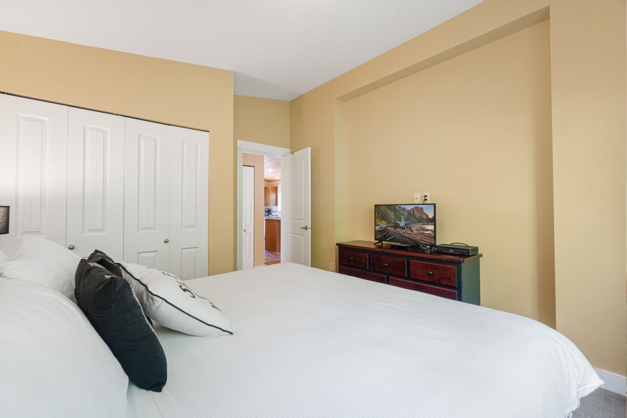 A bedroom with a large bed, a dresser, and a television.
