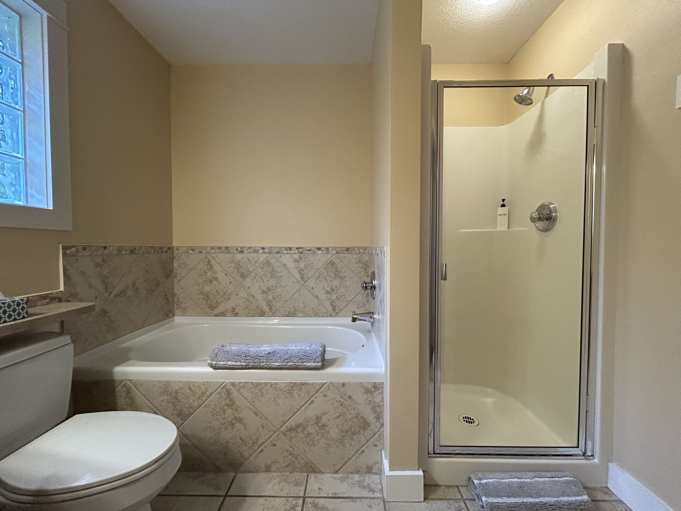 A bathroom with a toilet, a bathtub, and a shower stall.