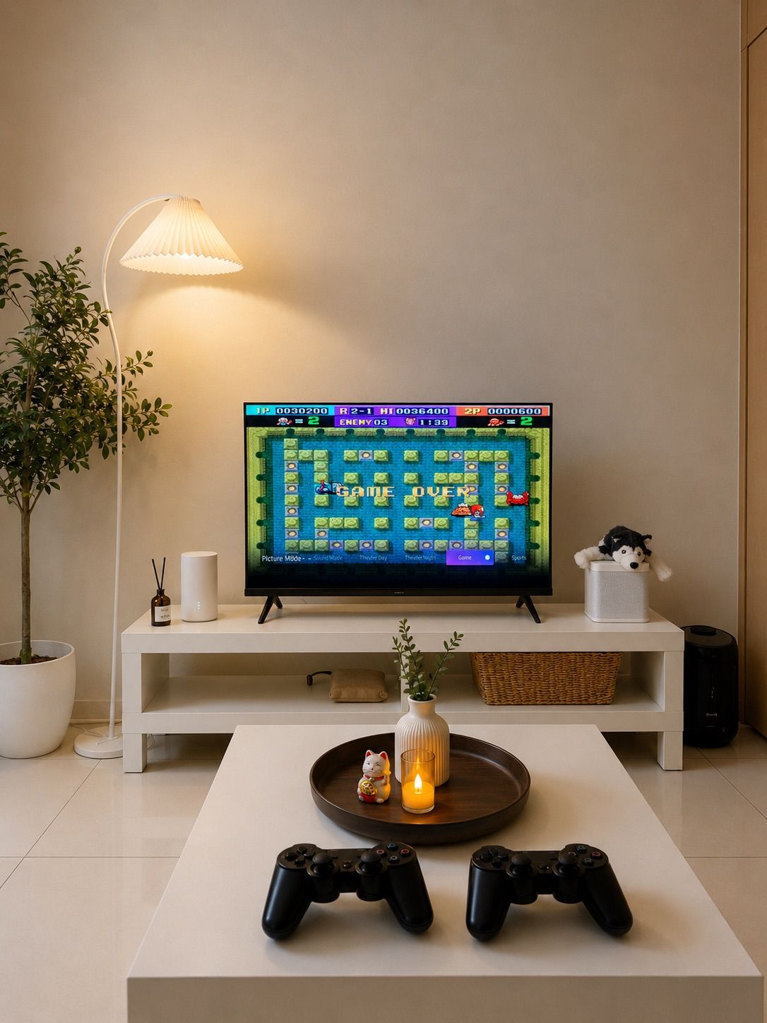 A modern living room with a television displaying a game, two game controllers on a coffee table, a potted plant, a lamp, and a small decorative item.