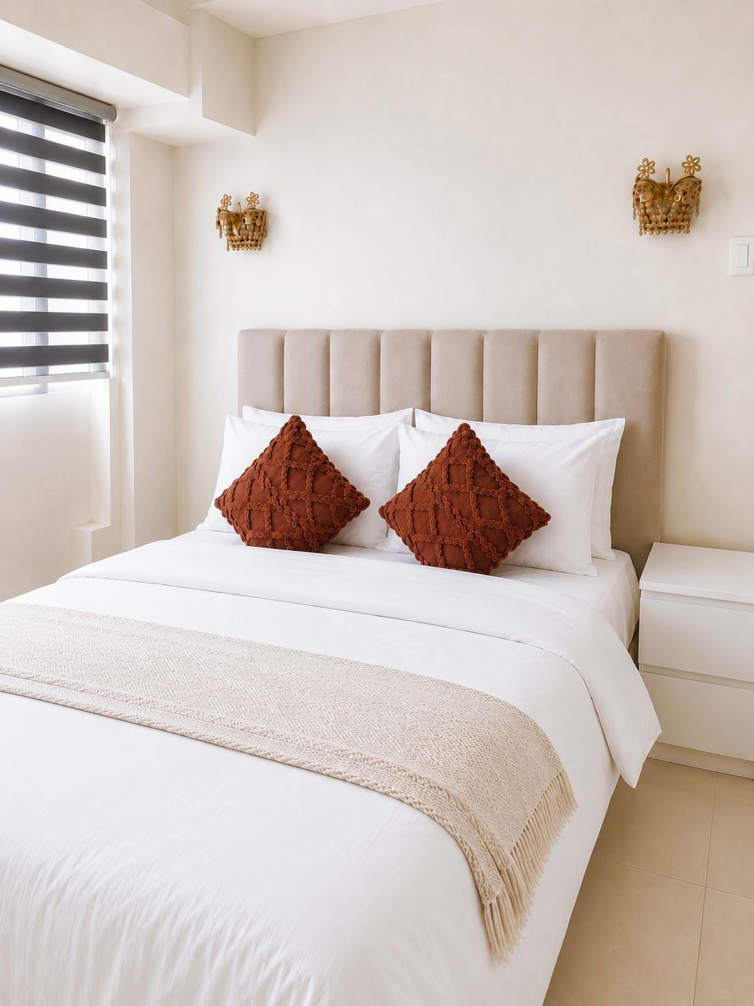 A neatly made bed with a headboard, two pillows, and a blanket.
