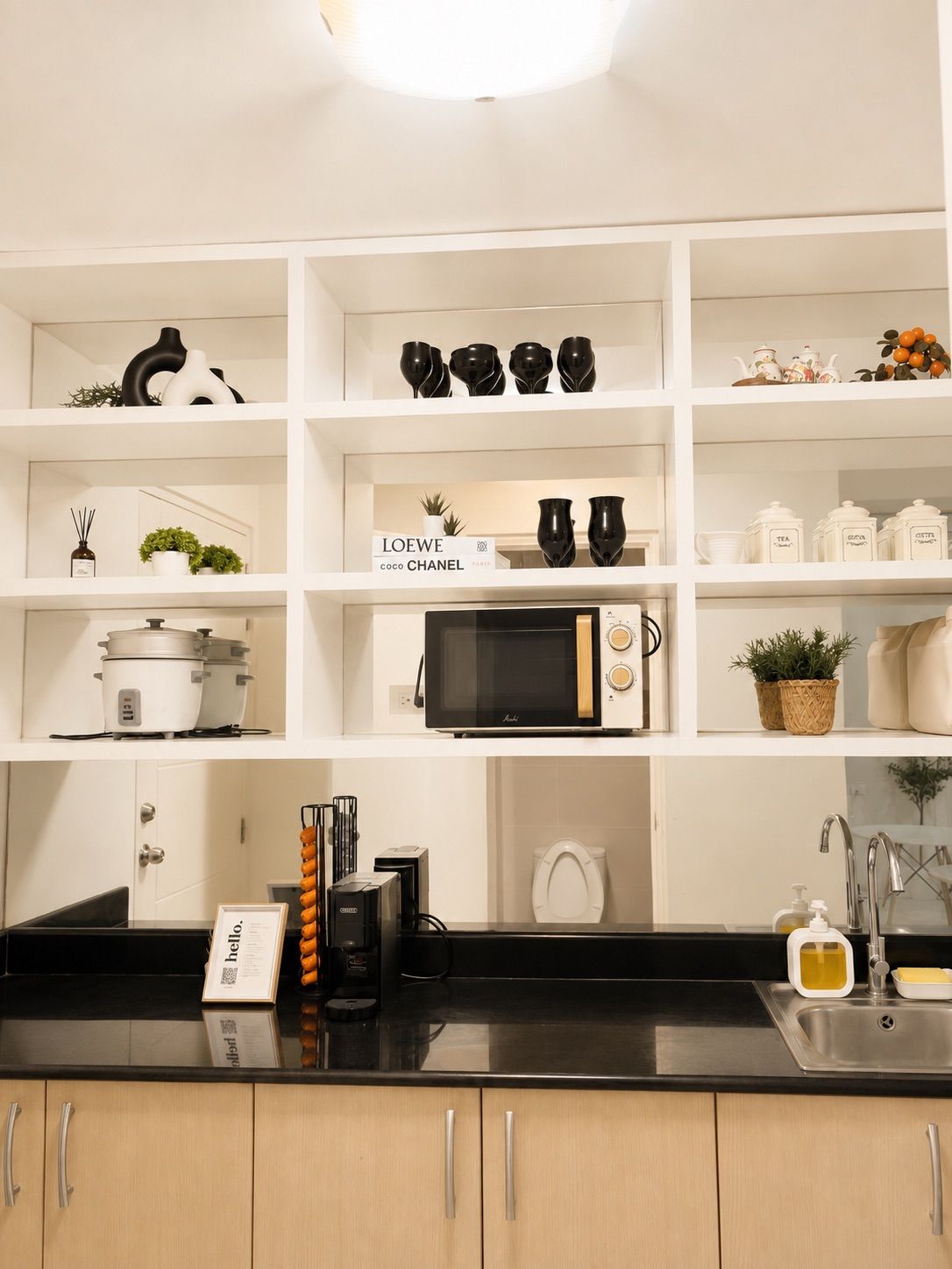 A kitchen with white shelving, a black countertop, and various kitchen appliances.
