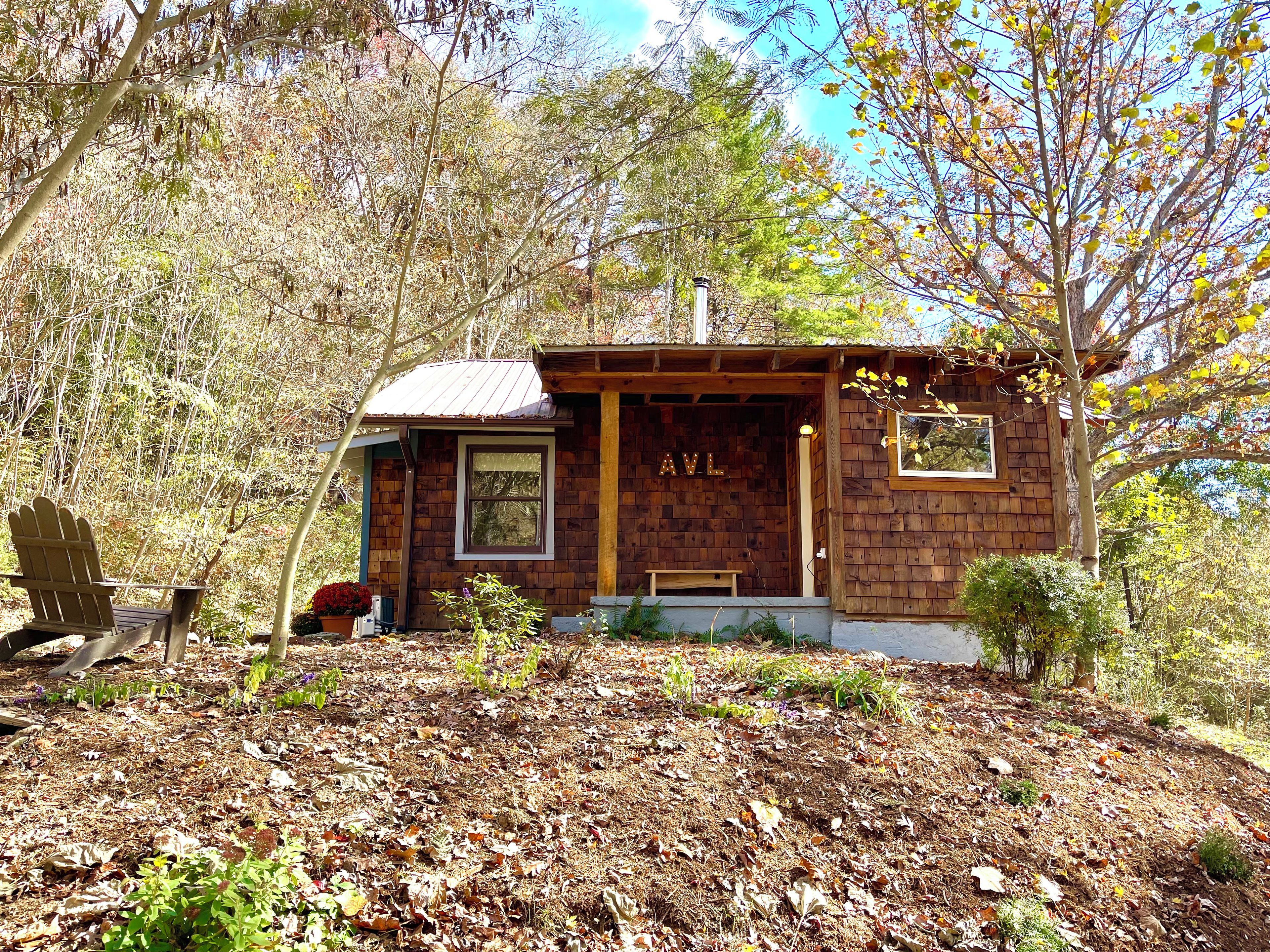 A small wooden cabin with a porch, a single window, and a door labeled 'AVL'.