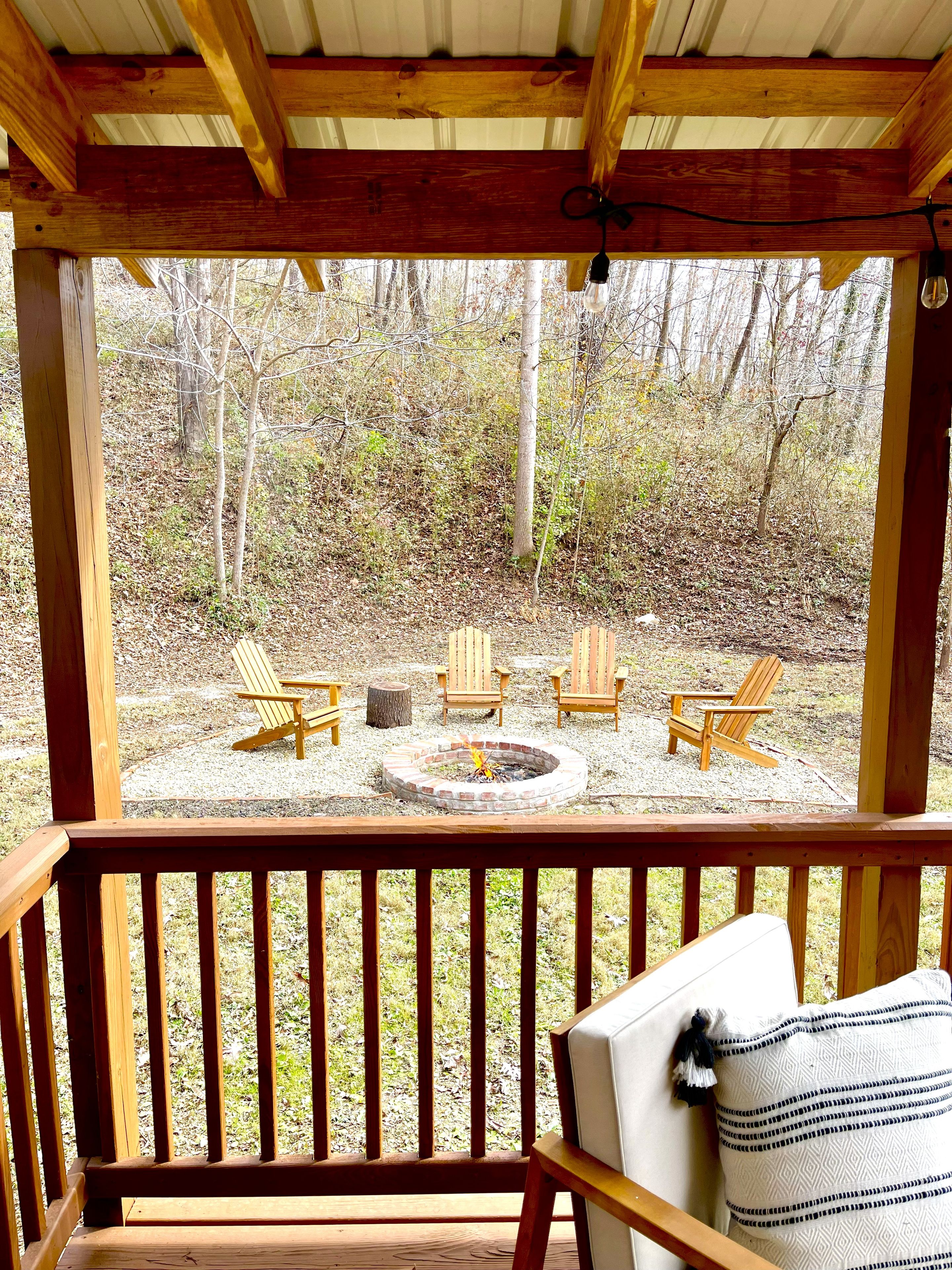 Una terraza de madera con un brasero y cuatro sillas tipo Adirondack.