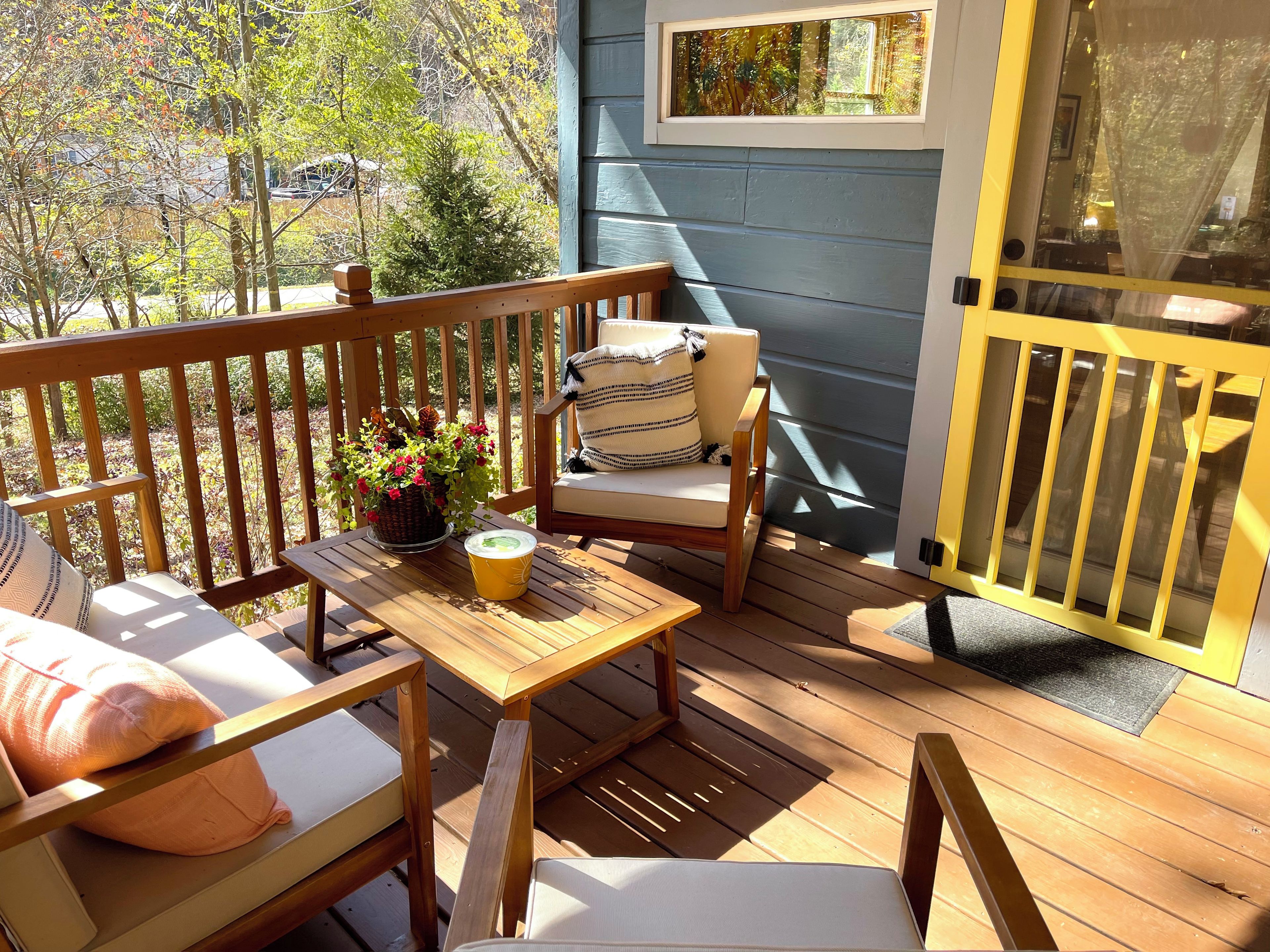 A wooden deck with outdoor furniture, including chairs and a table, and a door with a window.