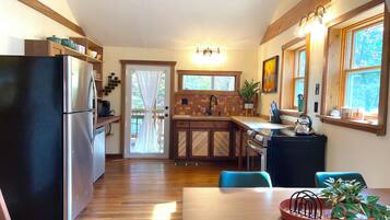 A kitchen with a refrigerator, stove, sink, and wooden cabinets.