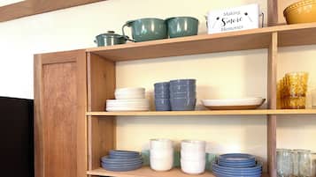 Una cocina con estantes de madera que exhiben diversos utensilios y un microondas.