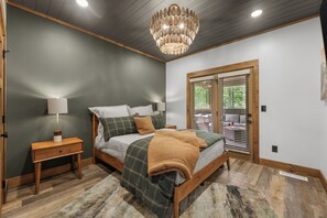 Une chambre à coucher avec un lit, des tables de chevet, une lampe, un lustre et une fenêtre avec des stores.