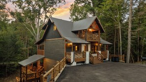 A cabin with a two-story structure, wooden exterior, and a porch with railings. - Sleeps 12, Game Room with Arcade, Air Hockey, PS5, Hot Tub (Sevierville)