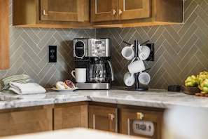 A kitchen with a coffee maker, a mug rack, and a plate of donuts. - Sleeps 12, Game Room with Arcade, Air Hockey, PS5, Hot Tub (Sevierville)