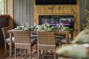 Un coin repas avec des chaises en osier et une table dressée pour quatre personnes, agrémenté d’assiettes vertes et de verres transparents.