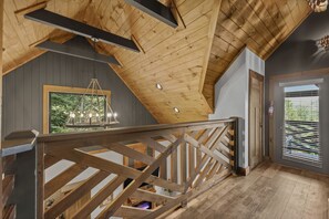 A wooden staircase with a railing, a hanging light fixture, and a door with blinds. - Sleeps 12, Game Room with Arcade, Air Hockey, PS5, Hot Tub (Sevierville)