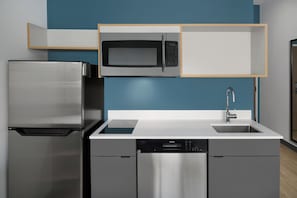 A modern kitchen with a stainless steel refrigerator, a microwave, and a dishwasher. - StudioRes by Marriott Mobile (Mobile)