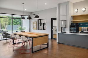A modern kitchen with a central island, bar stools, and a coffee station. - StudioRes by Marriott Mobile (Mobile)