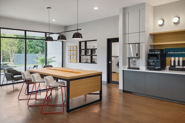 A modern kitchen with a central island, bar stools, and a coffee station.