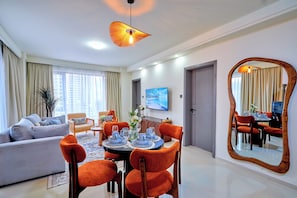 A modern living room with a dining area, featuring a large mirror, a sofa set, and a dining table with chairs. - 16th Floor Luxury -GTC Skyline Views with gym and workspace (Nairobi)