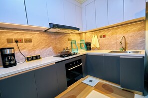 A compact kitchen with a stove, coffee maker, and a sink. - 16th Floor Luxury -GTC Skyline Views with gym and workspace (Nairobi)