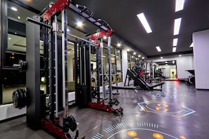 A gym with various exercise equipment, including a squat rack and benches. - 16th Floor Luxury -GTC Skyline Views with gym and workspace (Nairobi)