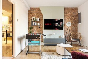 Living room with foosball table, Netflix TV and decorative brick wall- perfect for a social stay - Design-Led Shoreditch Flat | Graffiti • Brick Lane (Greater London)