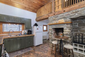A kitchen with wooden cabinets, a stone fireplace, and a bar area with stools.
