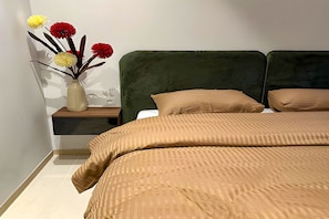 A bedroom with a bed, a nightstand, and a vase with flowers. - The Phoenician Pause (Tunis)