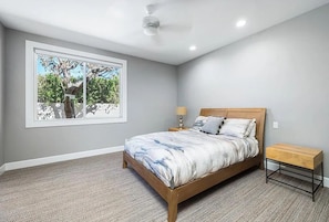 A bedroom with a large window, a bed, a bedside table, and a ceiling fan. - Soothing 3-bedroom /4bath house less than 1 mile from WTA Finals Indian Wells (Indian Wells)