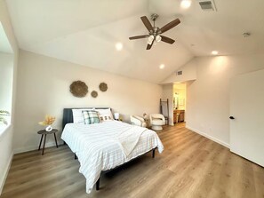 A bedroom with a bed, a ceiling fan, a small table with a vase, and a chair. - The Shenandoah Sanctuary: A Fully Furnished Modern Retreat (Richmond)