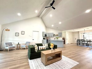 A spacious living area with a green sofa, a wooden coffee table, and a kitchen in the background. - The Shenandoah Sanctuary: A Fully Furnished Modern Retreat (Richmond)