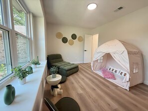 A room with a play tent, a green sofa, a round table, and potted plants. - The Shenandoah Sanctuary: A Fully Furnished Modern Retreat (Richmond)