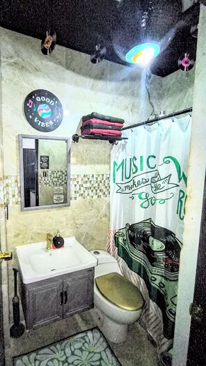 Un bagno con lavandino, WC e tenda della doccia con motivo musicale.