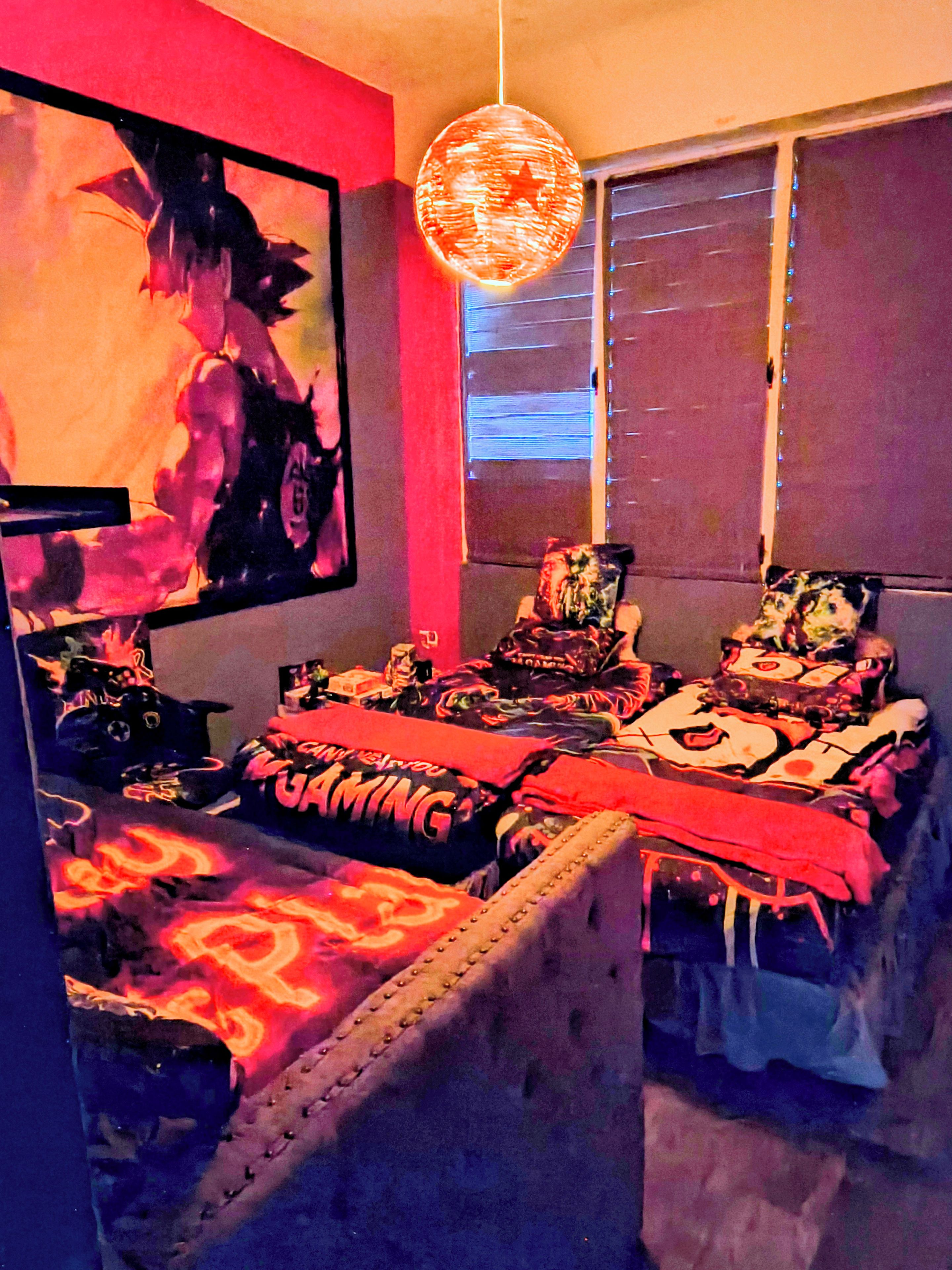 Een kamer met een game-thema, met een bed, posters van games en een hanglamp.