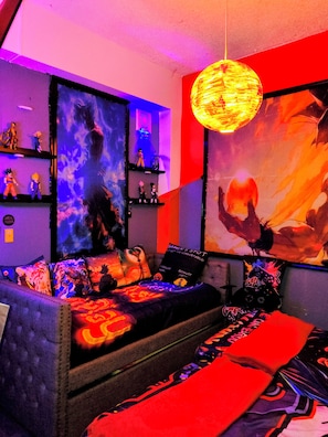 A room with a sofa, a wall-mounted shelf with figurines, and a large poster.