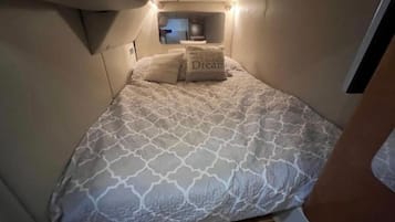 Un dormitorio pequeño y acogedor con cama, almohadas y mesita de noche.