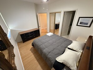 Una camera da letto con un letto, una cassettiera e una porta che dà su un'altra stanza.