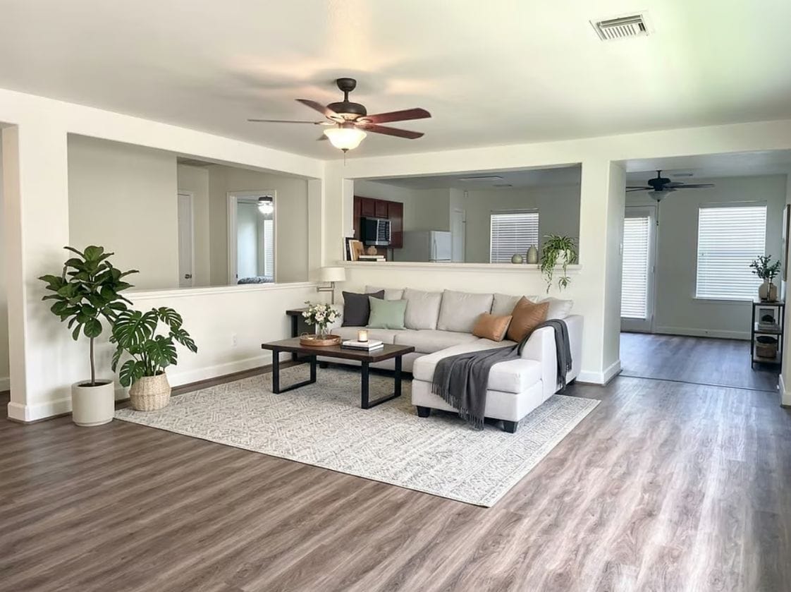 A spacious living room with a white sofa, a coffee table, and a ceiling fan.