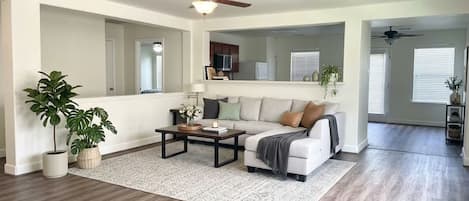 Un salon spacieux avec un canapé blanc, une table basse et un ventilateur de plafond.