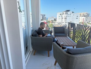 A balcony with wicker furniture, a laptop, and a view of the cityscape. - Spectacular 1-bedroom 2 bath luxury penthouse in Zona Romantica. Top 1% listing. (Puerto Vallarta)