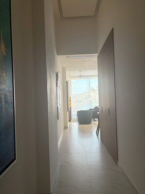 Een gang met zicht op een balkon, een plafondventilator en een zithoek met een stoel.