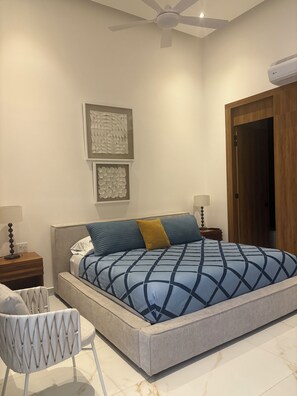 A bedroom with a bed, a chair, a ceiling fan, and a door. - Spectacular 1-bedroom 2 bath luxury penthouse in Zona Romantica. Top 1% listing. (Puerto Vallarta)