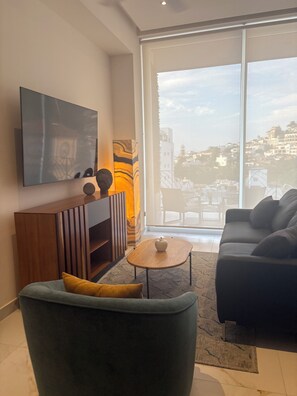 A modern living room with a sofa, a coffee table, and a TV mounted on the wall. - Spectacular 1-bedroom 2 bath luxury penthouse in Zona Romantica. Top 1% listing. (Puerto Vallarta)