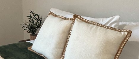 A bed with a dark green bedspread and two pillows with a decorative border.