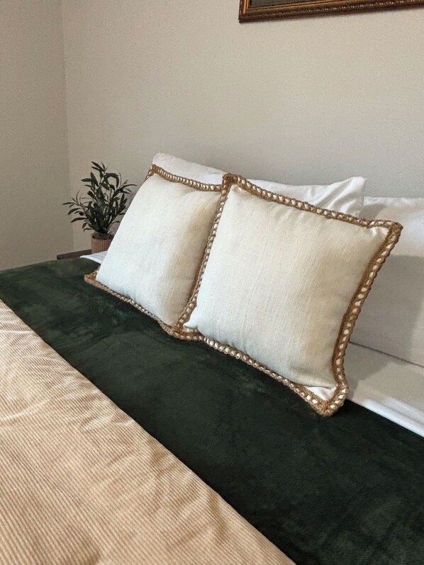 Una cama con una colcha verde oscuro y dos almohadas con un borde decorativo.