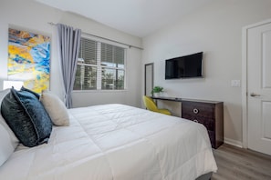 A bedroom with a bed, a desk, a TV, and a window with blinds. - Vista Cay 2BR Condo King Suite Near Universal (Orlando)